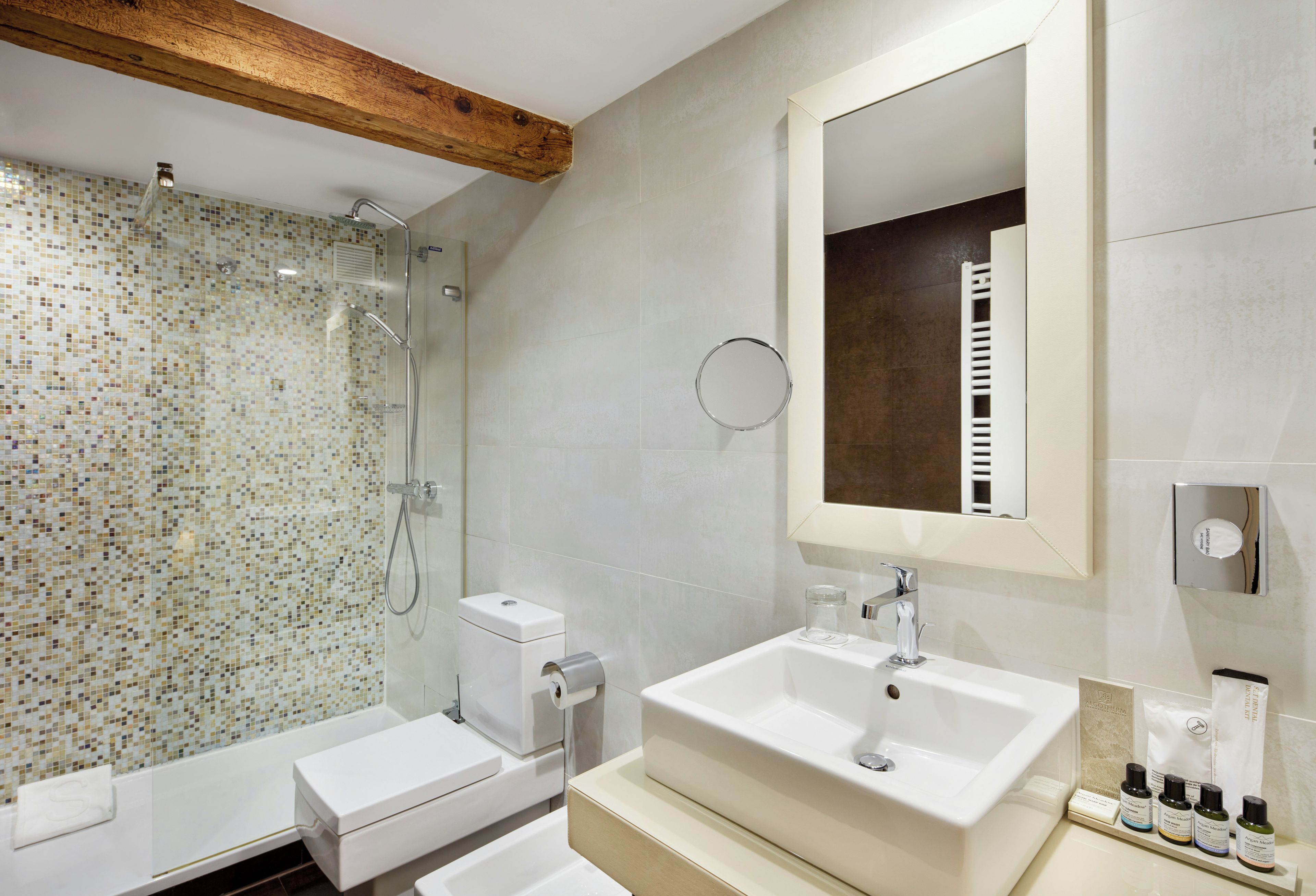 Un baño moderno con ducha, inodoro, lavabo y espejo.