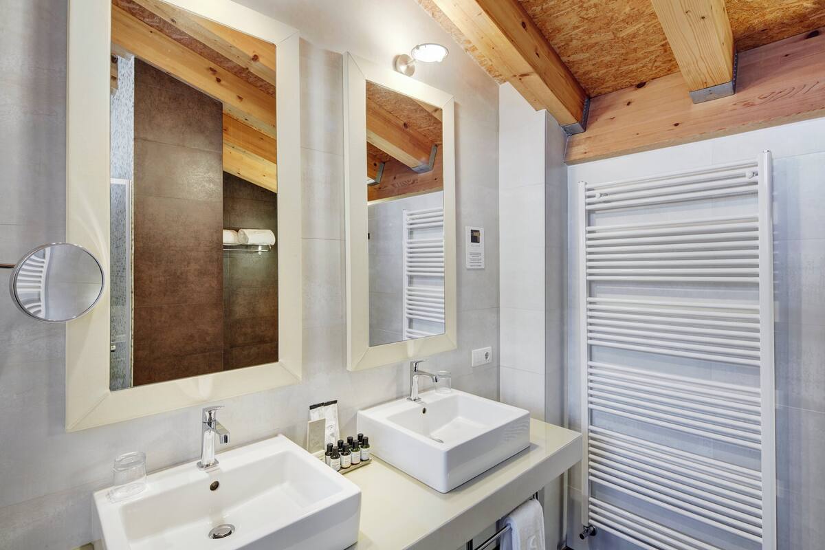 A modern bathroom with two sinks, large mirrors, and a towel rack.