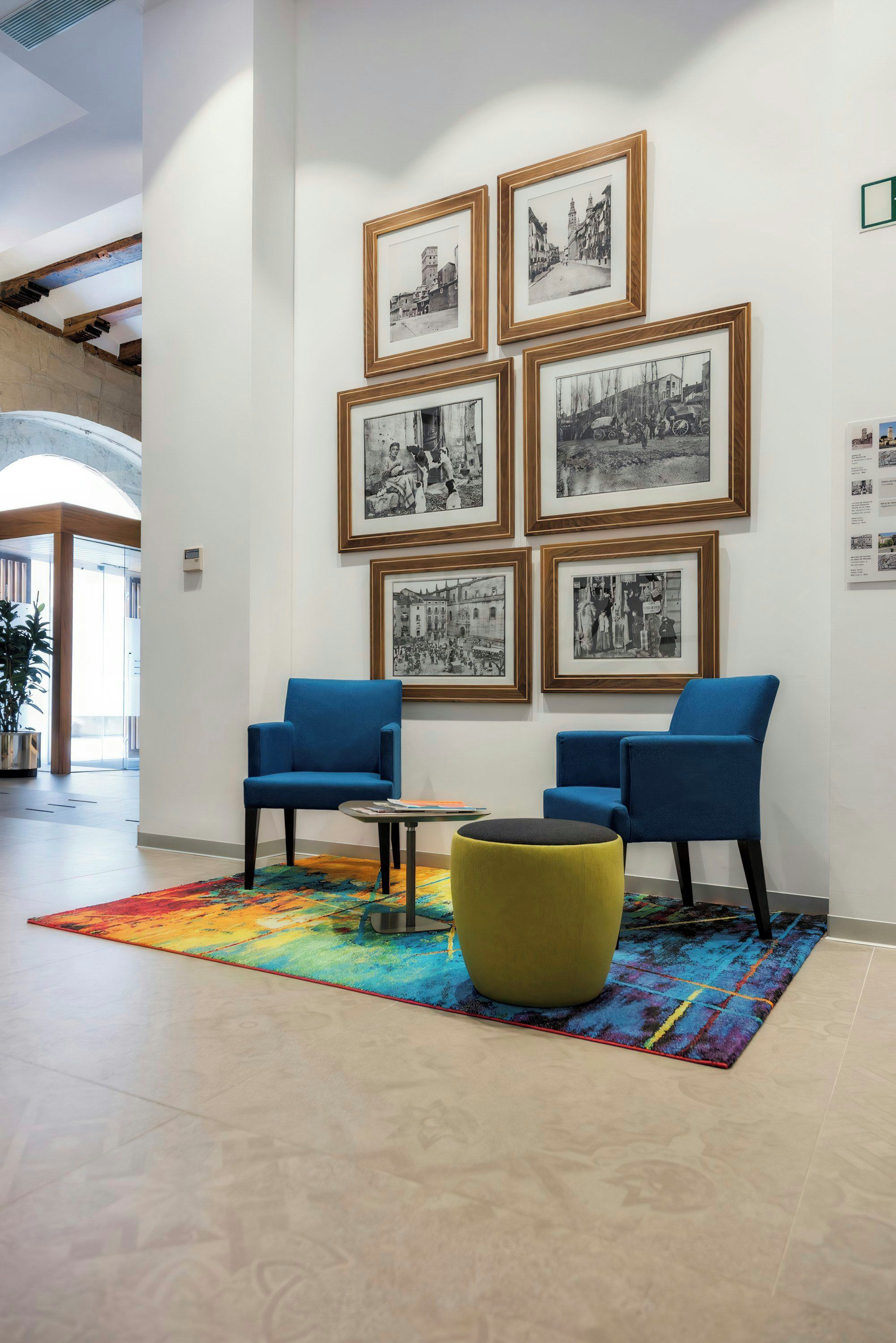 Un'area di sosta nella hall, un tappeto colorato e una parete con fotografie in bianco e nero incorniciate.