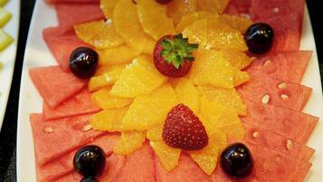 A fruit platter with watermelon, orange slices, strawberries, and blueberries arranged on a white plate.