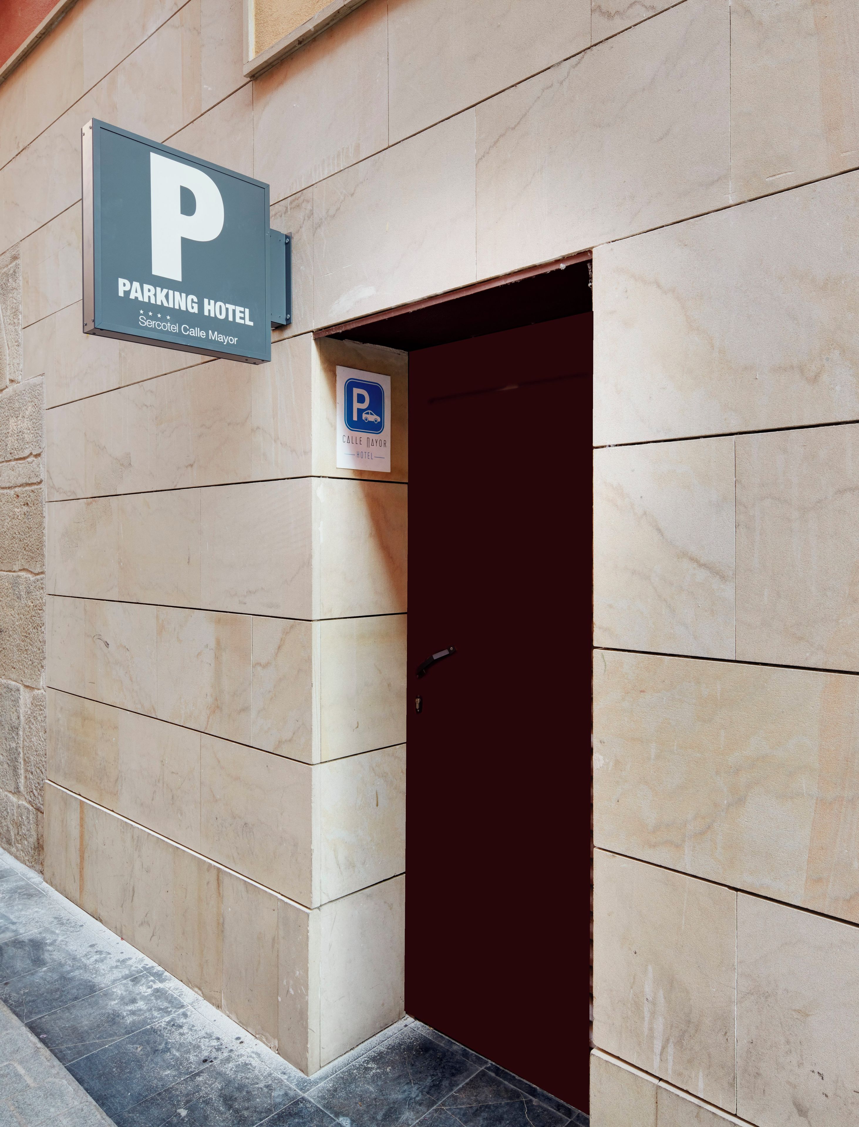 Entrada de un hotel con un cartel de estacionamiento y una puerta.