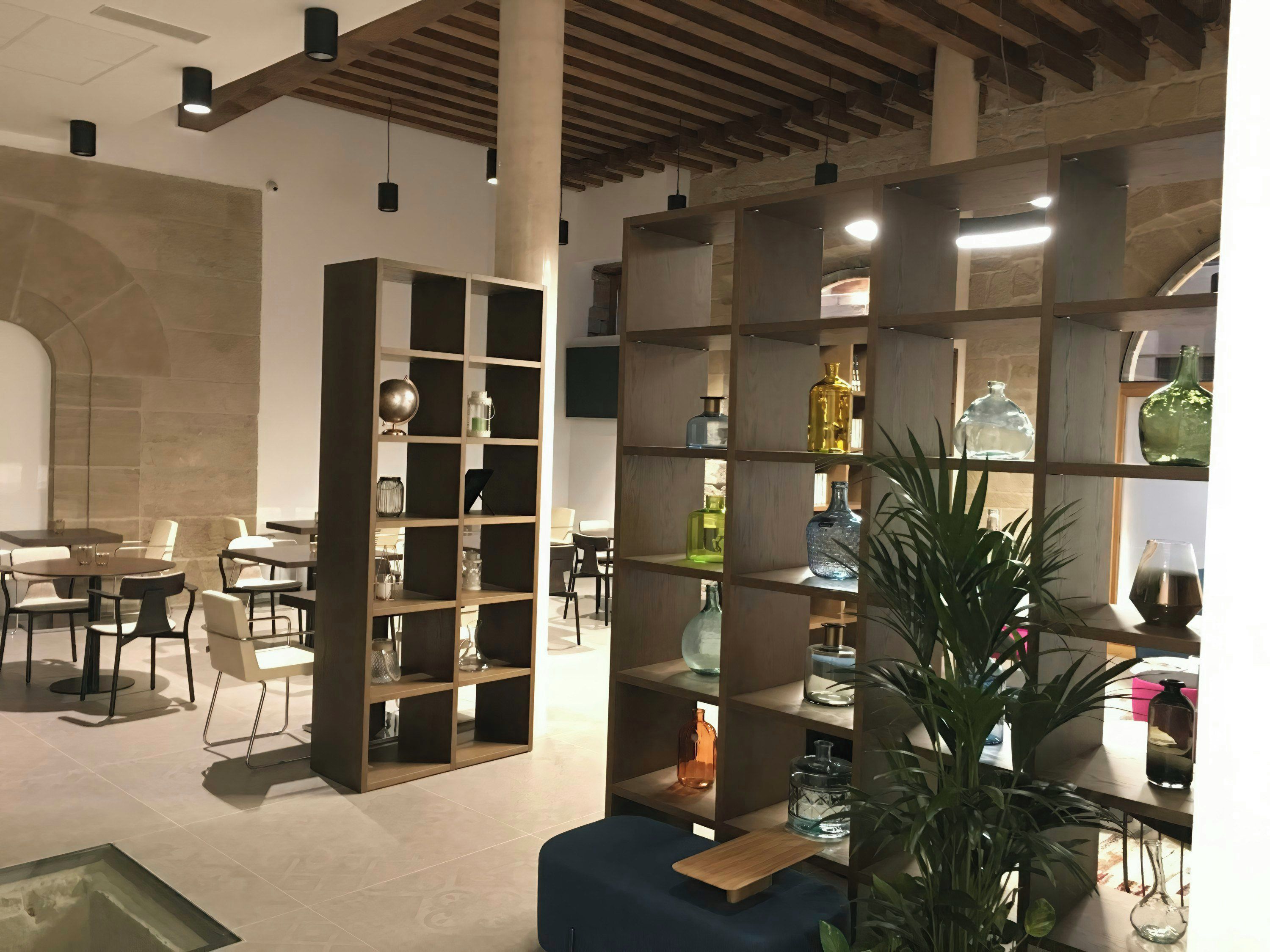 Ein modernes Interieur mit einer zentralen Sitzecke, einem Holzregal und einem Essbereich.
