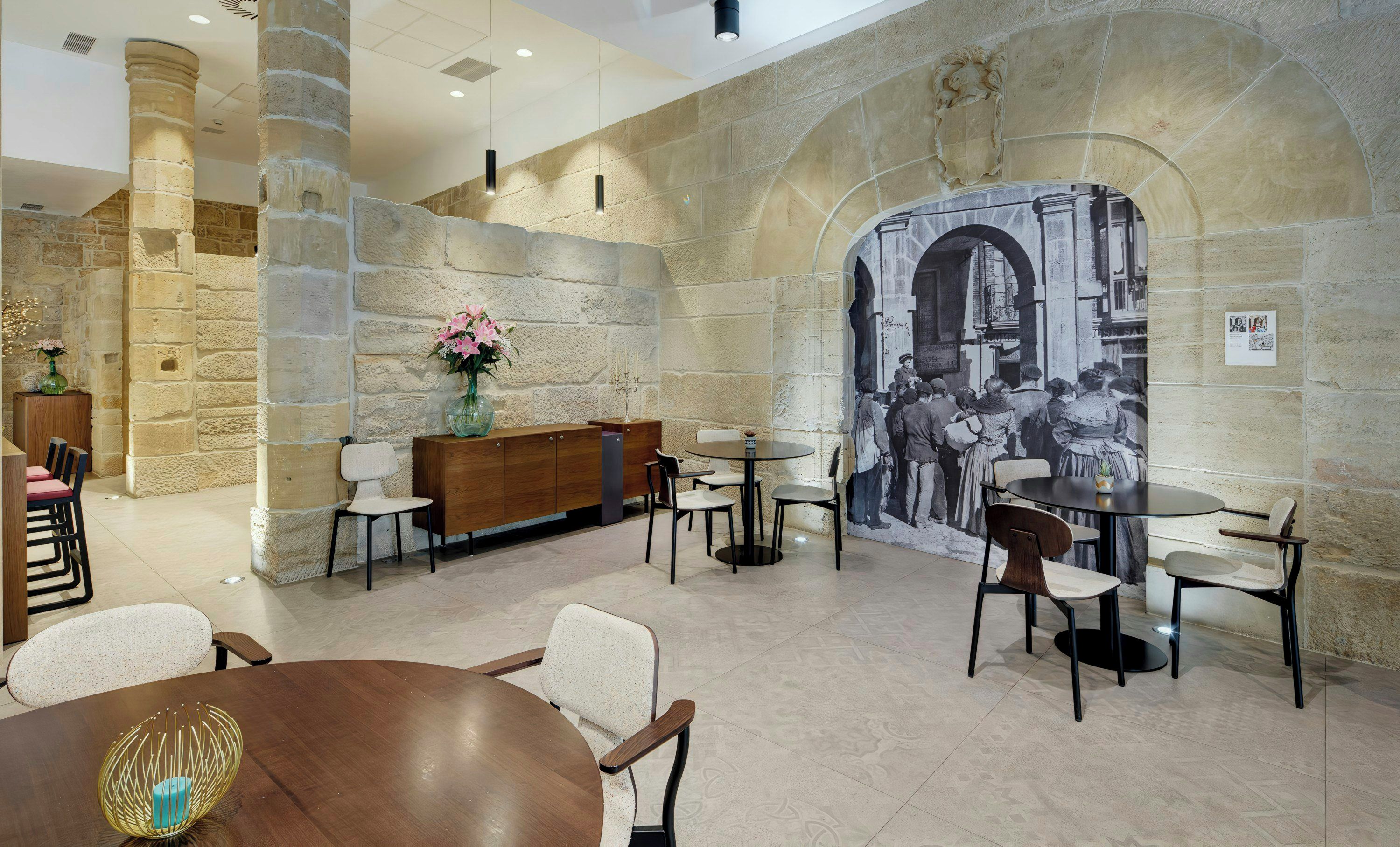 Vestíbulo con paredes de piedra, un mural, asientos y un mostrador de recepción.