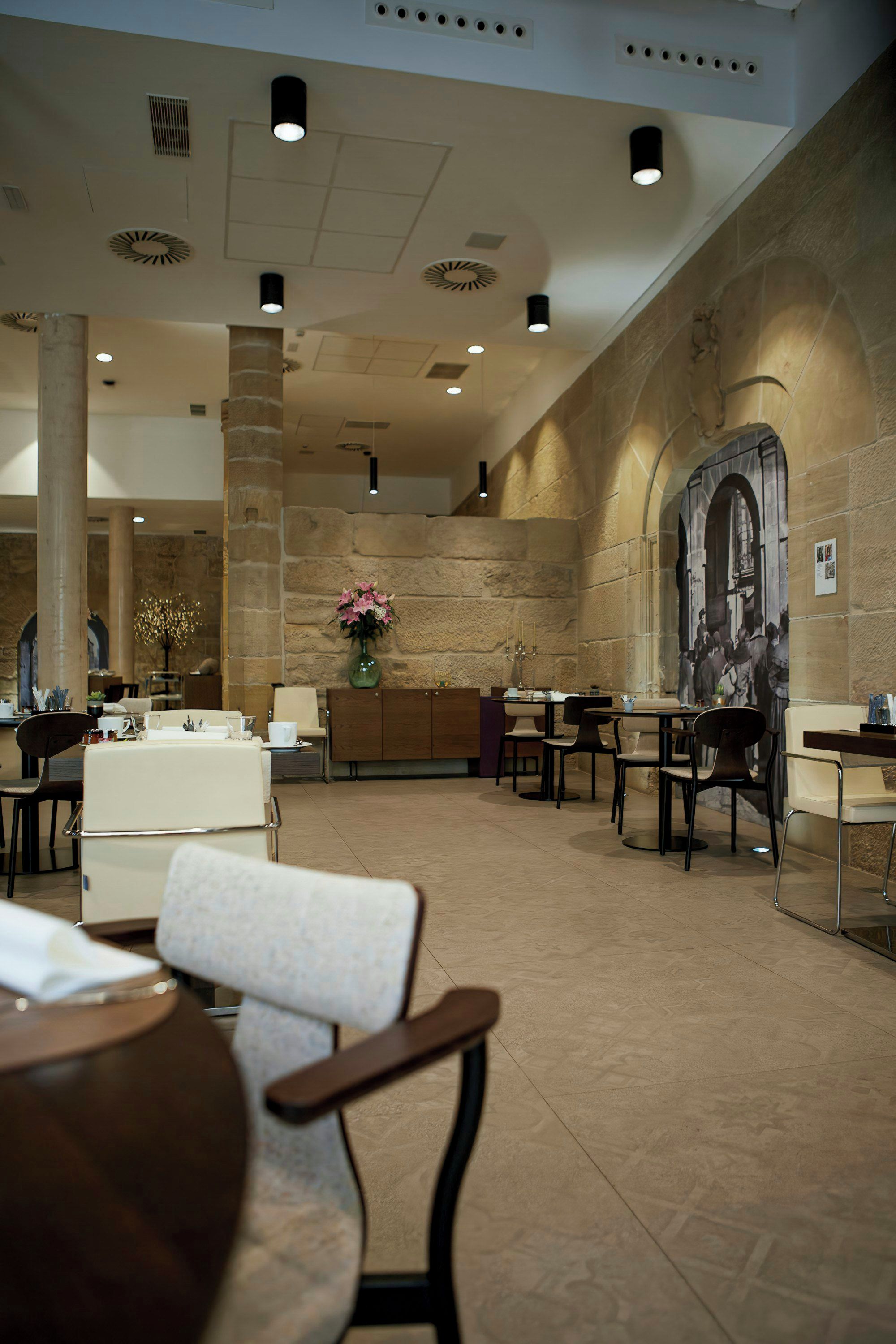 A spacious lobby with multiple seating areas, a central floral arrangement, and a large mural on the wall.