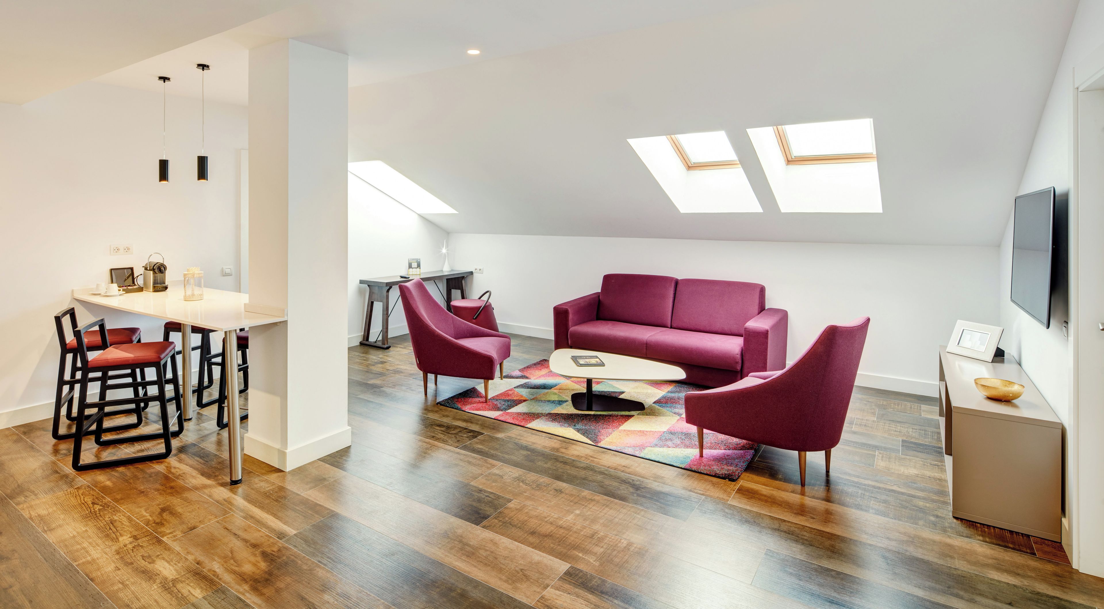 A modern living room with a sofa, chairs, a coffee table, and a TV.