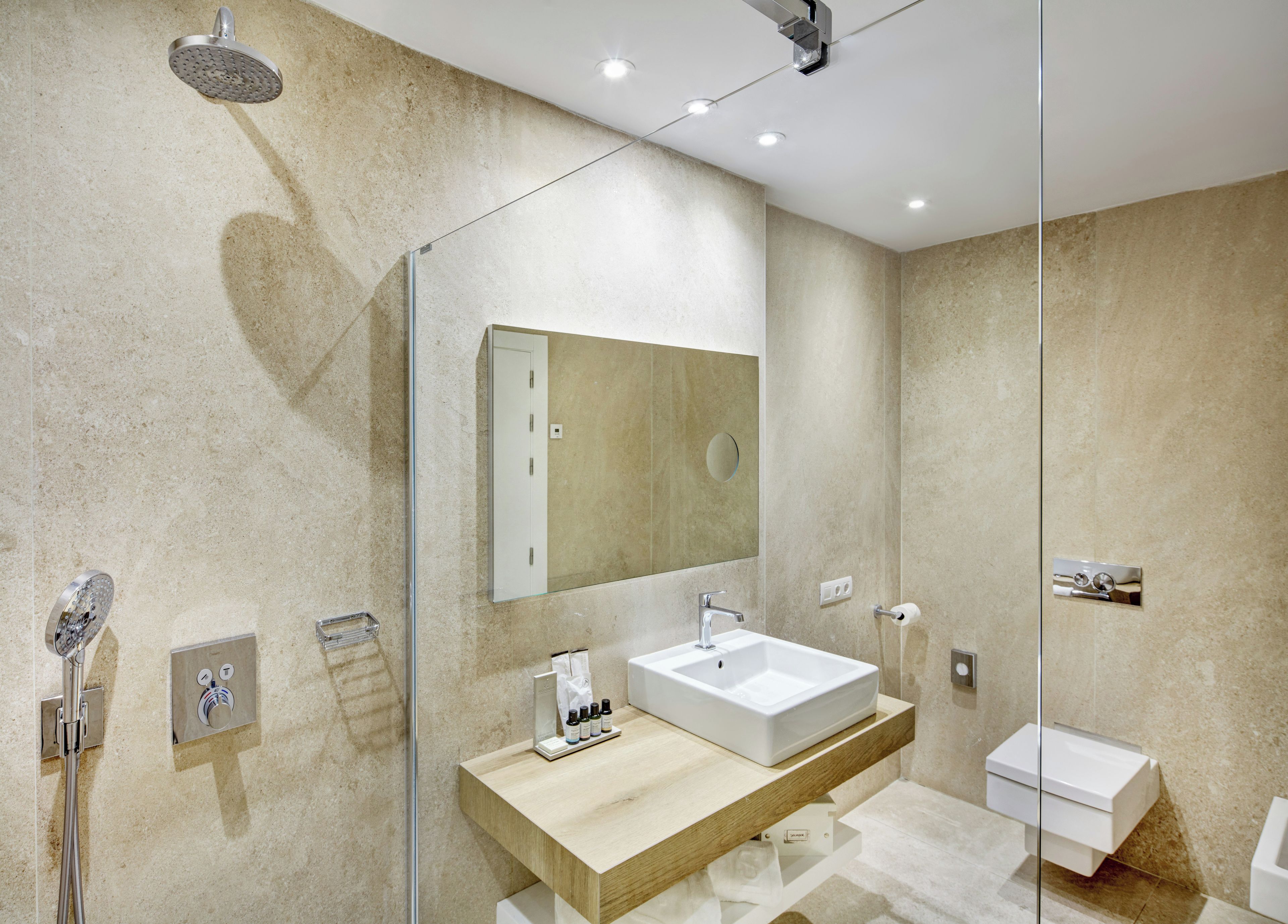 A modern bathroom with a glass-enclosed shower, a large mirror, a wooden vanity, and a white sink.