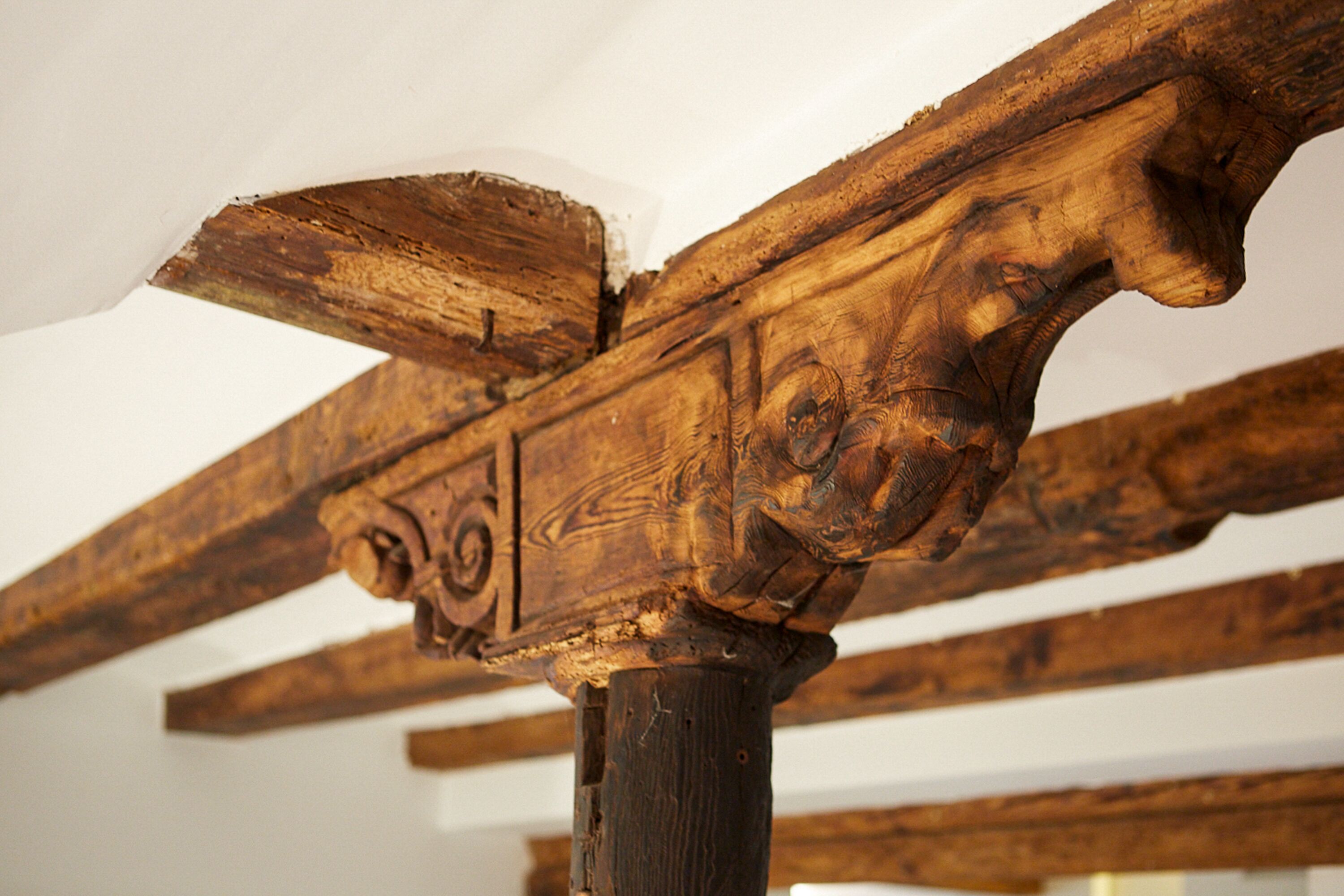 Una viga de madera con detalles tallados, parte de la estructura del techo.