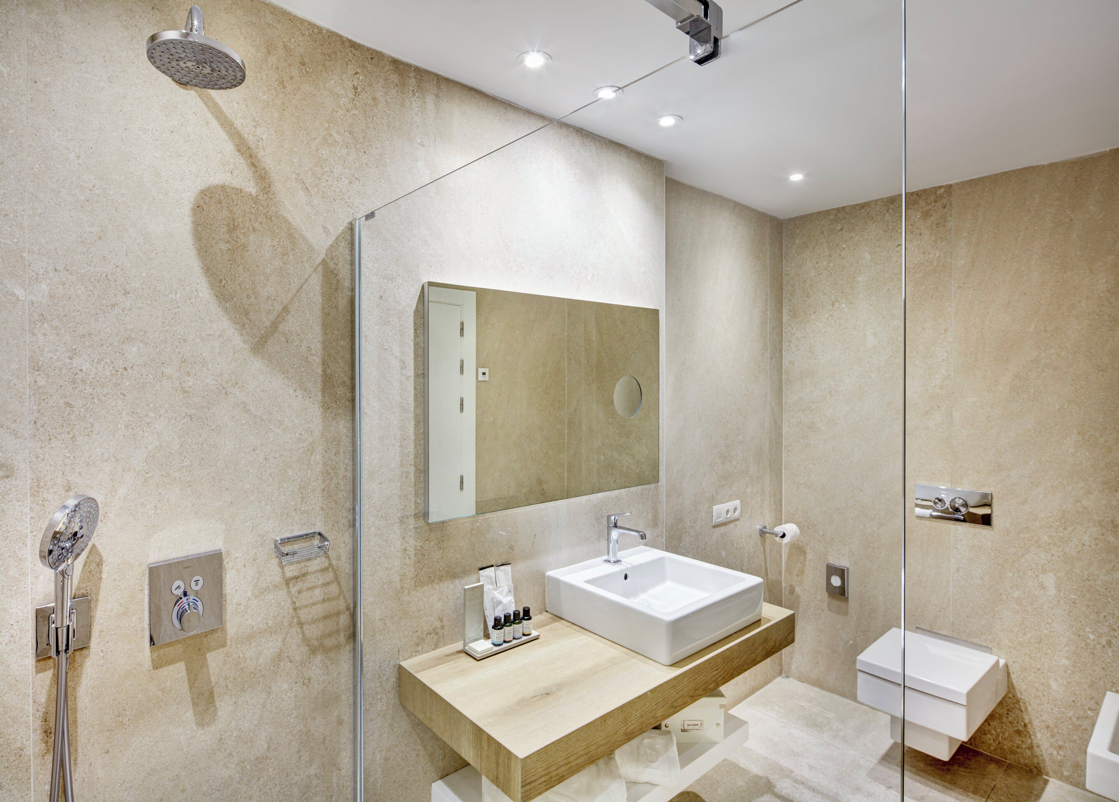 Un bagno moderno con doccia vetrata, uno specchio grande, un mobile vanitario in legno e una zona lavabo separata.