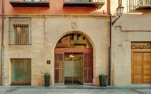 Fachada de edifício com uma ampla entrada em arco, porta de madeira e janela com grade.
