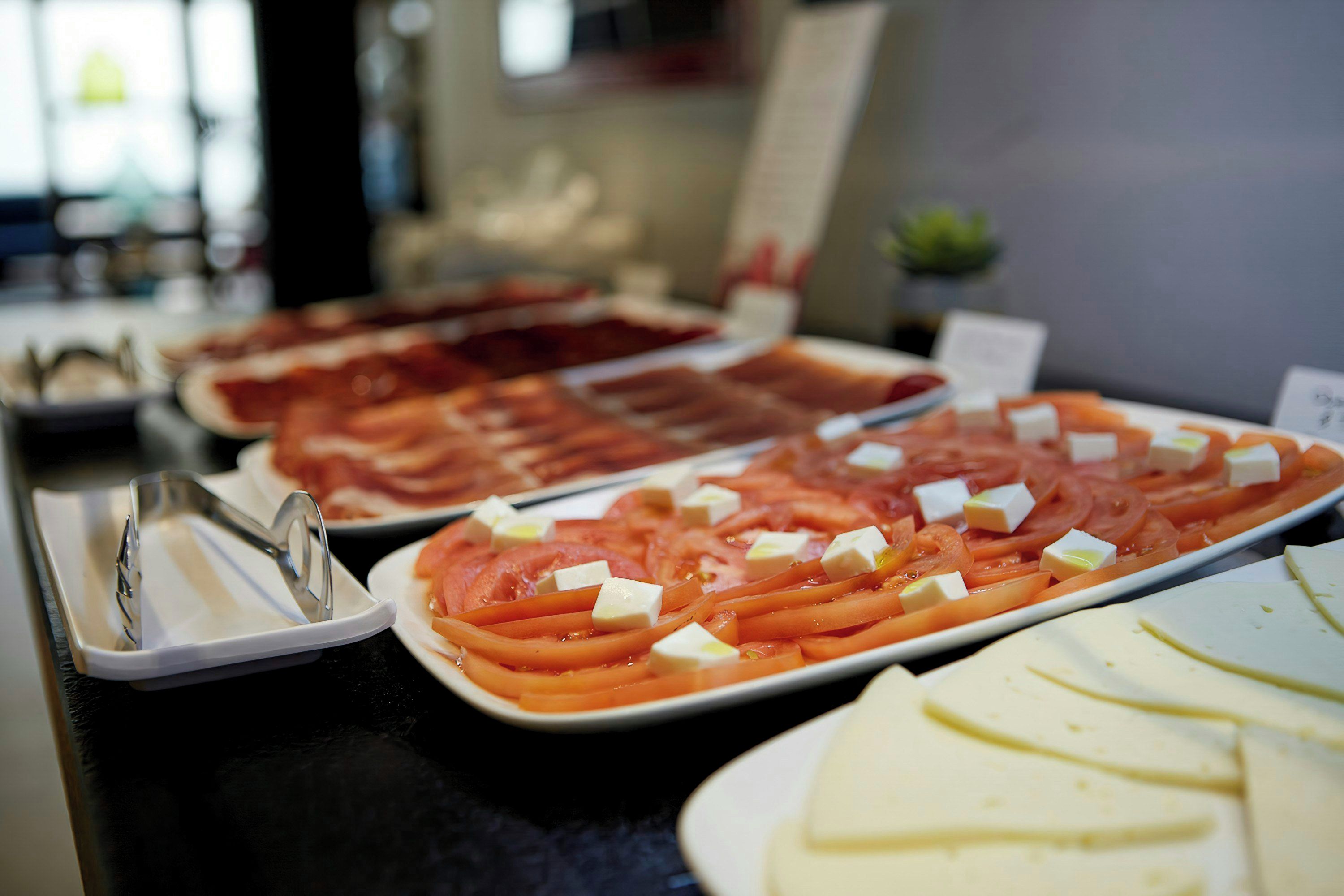A buffet with various food items including sliced meats and cheeses.