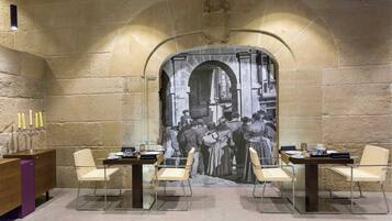 Un comedor con un mural, mesas, sillas y un candelabro.