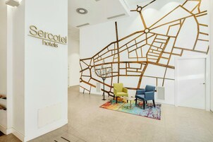 Vestíbulo de hotel con una instalación de mapa, dos sillas y una alfombra colorida.