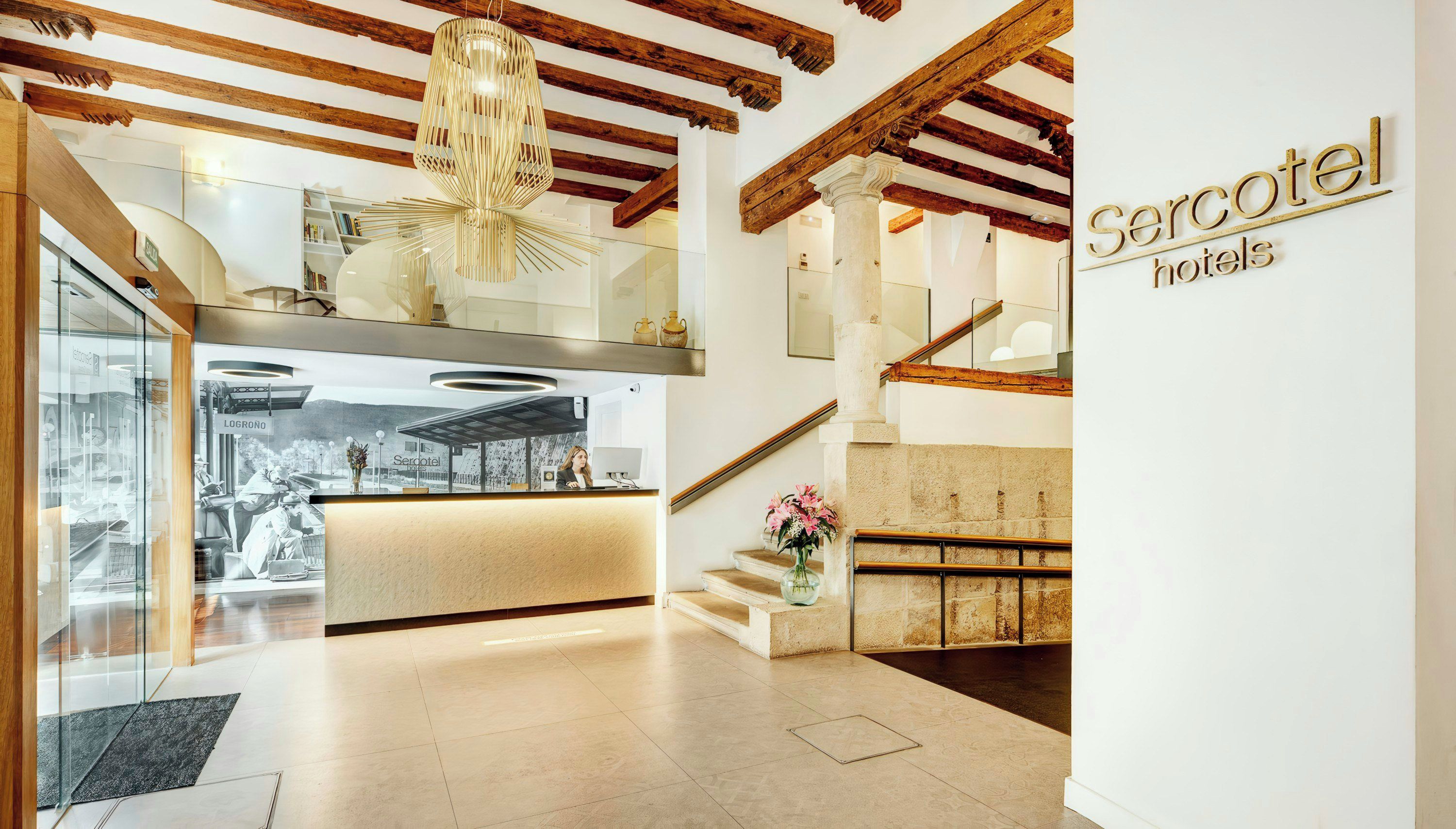 Ein Hotel-Empfangsbereich mit modernem Design, einer Treppe und einem Schild für 'Serotel hotels'.