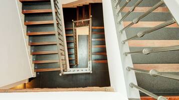 Uma escadaria moderna com guarda-corpo em madeira e metal, que leva a um andar superior.