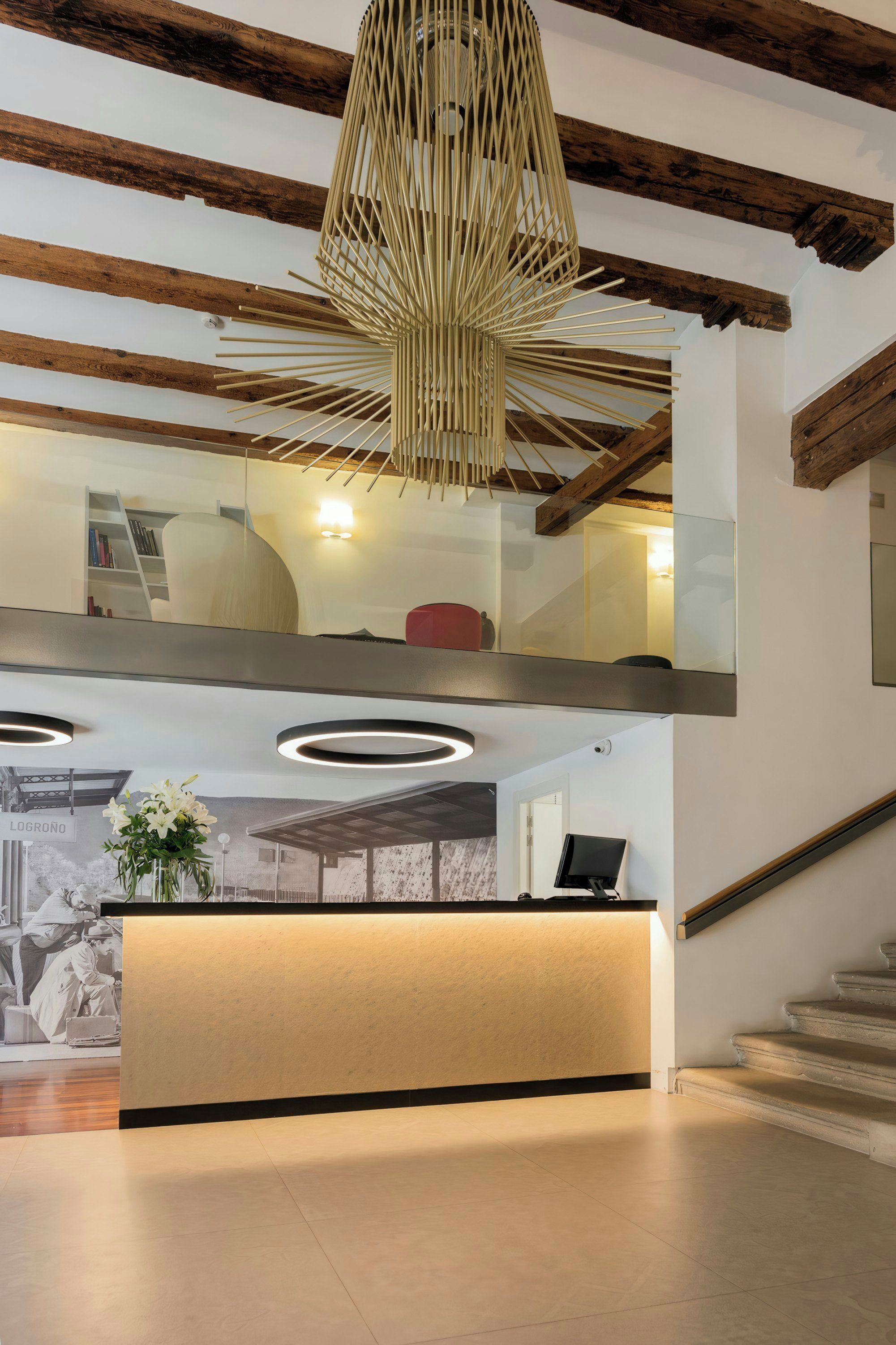Zona de recepción con techo de madera, lámpara moderna y mostrador.