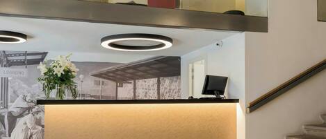 A reception area with a wooden ceiling, a modern light fixture, and a reception desk.