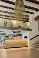 Zona de recepción con techo de madera, lámpara moderna y mostrador.