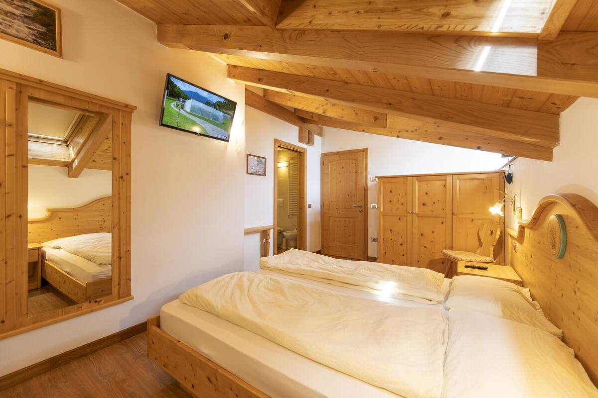 A wooden bedroom with a large bed, a TV on the wall, and wooden cabinets.