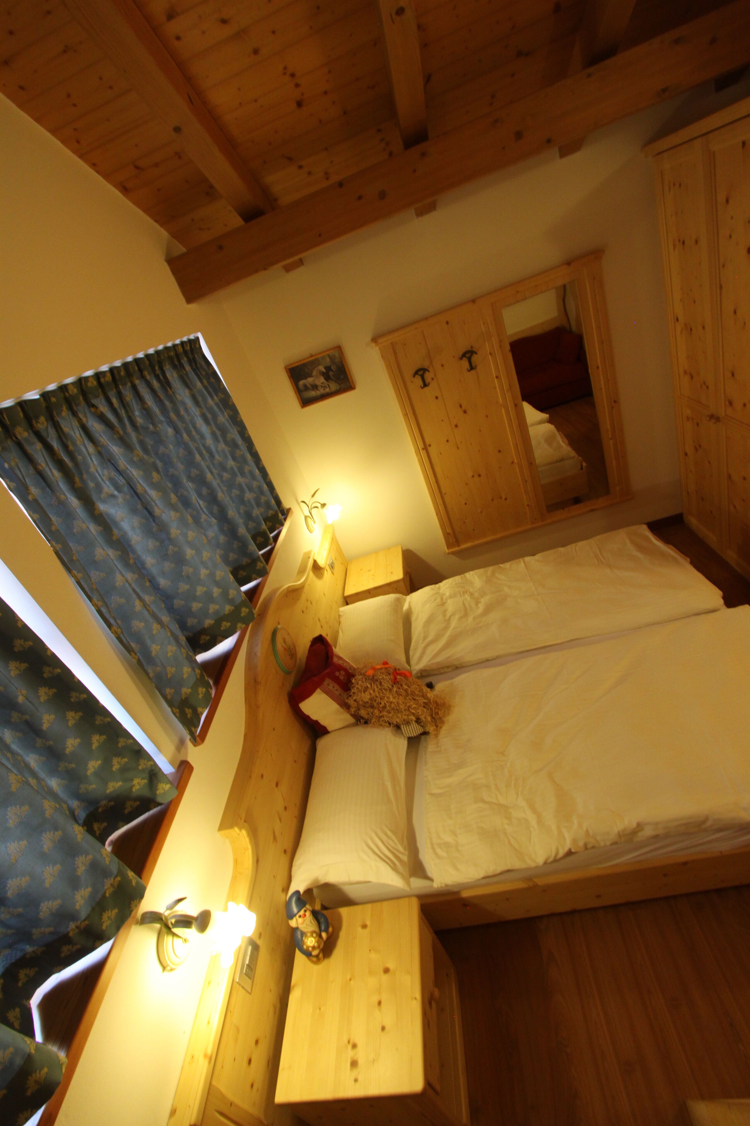 Une chambre à coucher avec un cadre en bois, comprenant un lit, une table de chevet, une commode et un miroir.