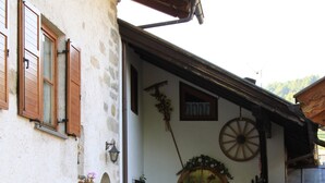 A stone building with a wooden door, steps leading up to the entrance, and a sign in front. - Affittacamere Corradini (Castello-Molina di Fiemme)