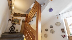 A staircase with wooden railings and a wall decorated with various plates and a small figurine. - Affittacamere Corradini (Castello-Molina di Fiemme)