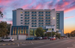A multi-story hotel with a modern facade, a gated entrance, and several parked cars. - DoubleTree by Hilton Hotel Oradea (Oradea)