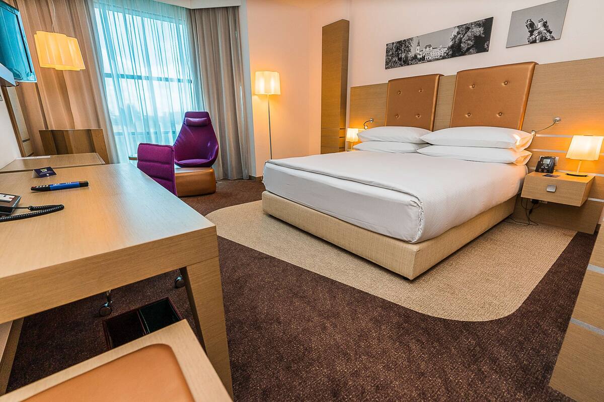 Una habitación de hotel con cama, escritorio, silla y mesita de noche.