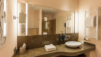 Une salle de bain moderne avec un grand miroir, un lavabo et un porte-serviettes.