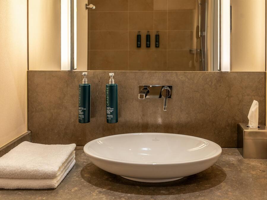 A bathroom with a large white sink, a towel, and two hand wash bottles.