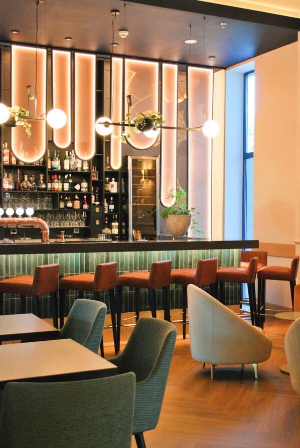 A bar area with a long counter, multiple seating options including bar stools and chairs, and a large potted plant. - DoubleTree by Hilton Hotel Oradea (Oradea)