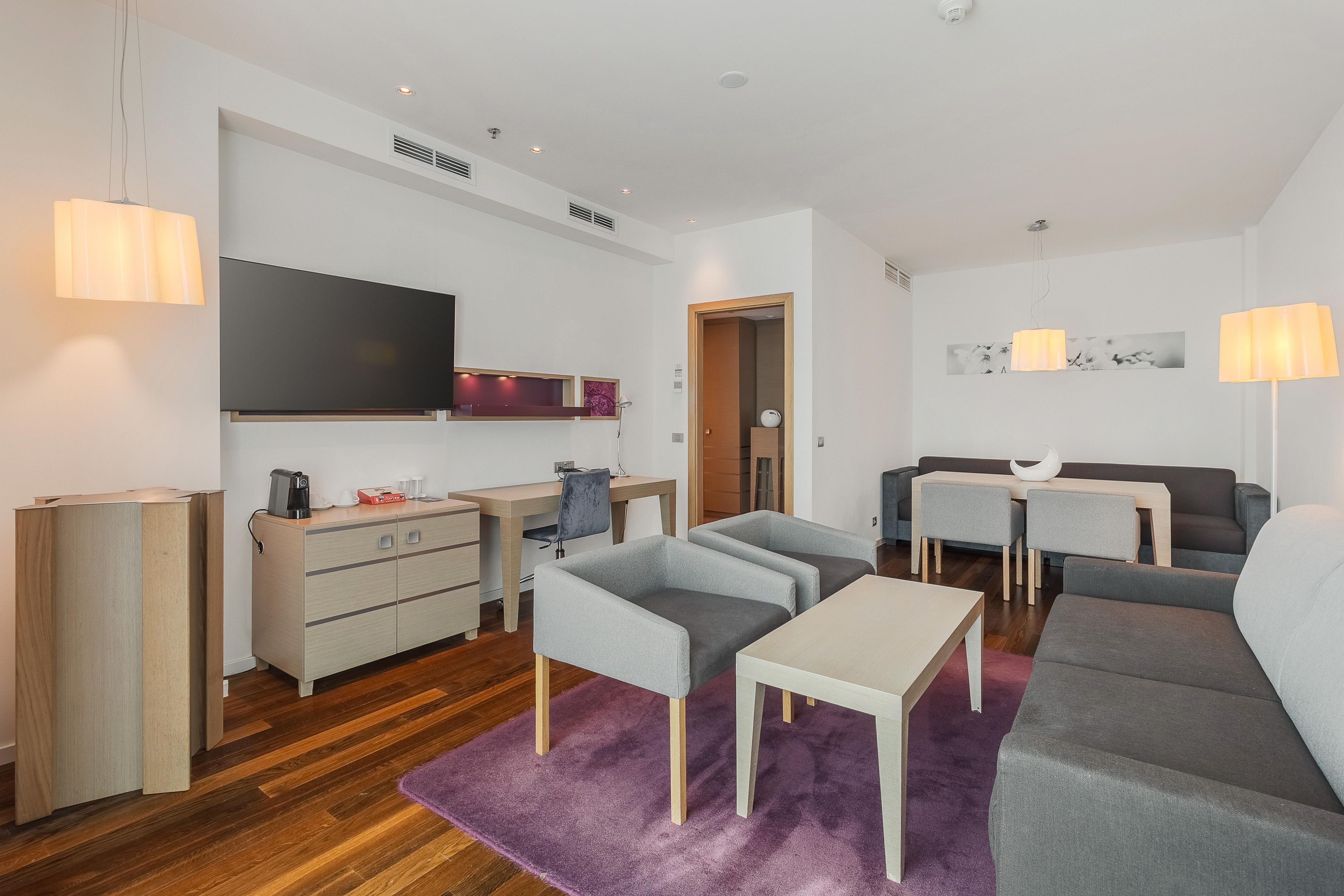 Una sala de estar moderna con un sofá, sillones, una mesa de centro y un televisor.