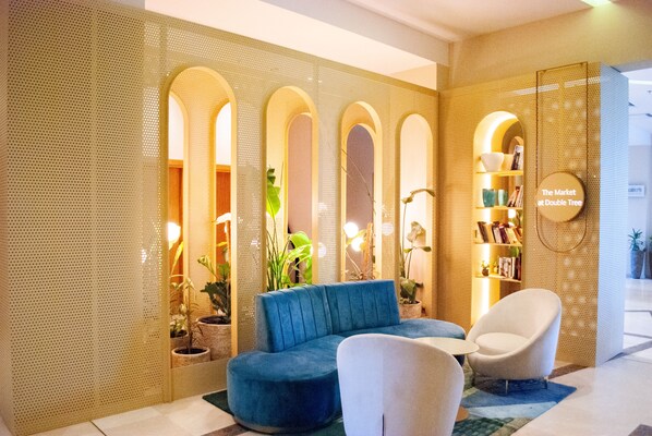 Un intérieur moderne avec un canapé bleu, un fauteuil blanc et une bibliothèque.