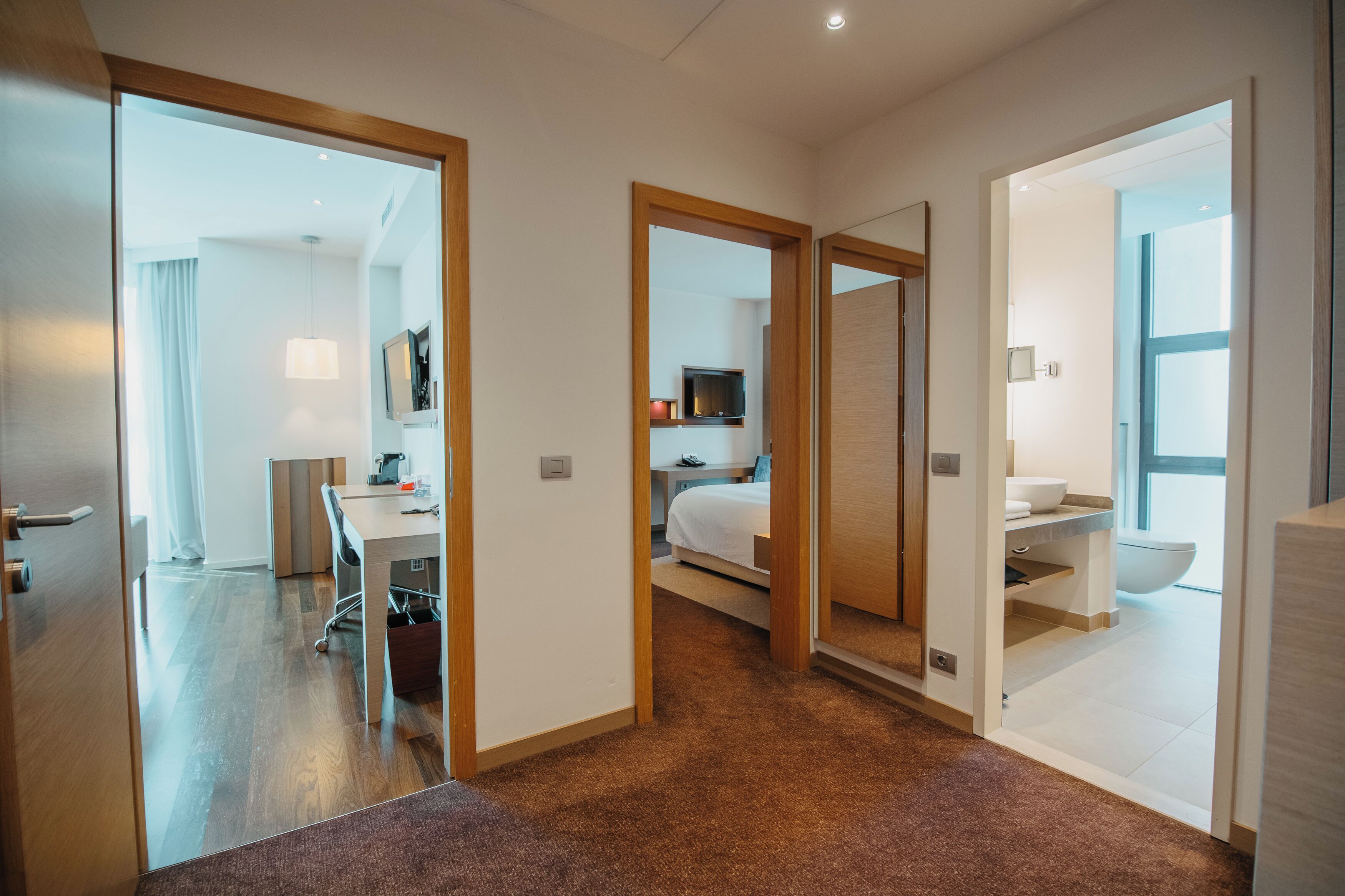A hotel room with a bed, desk, and bathroom.