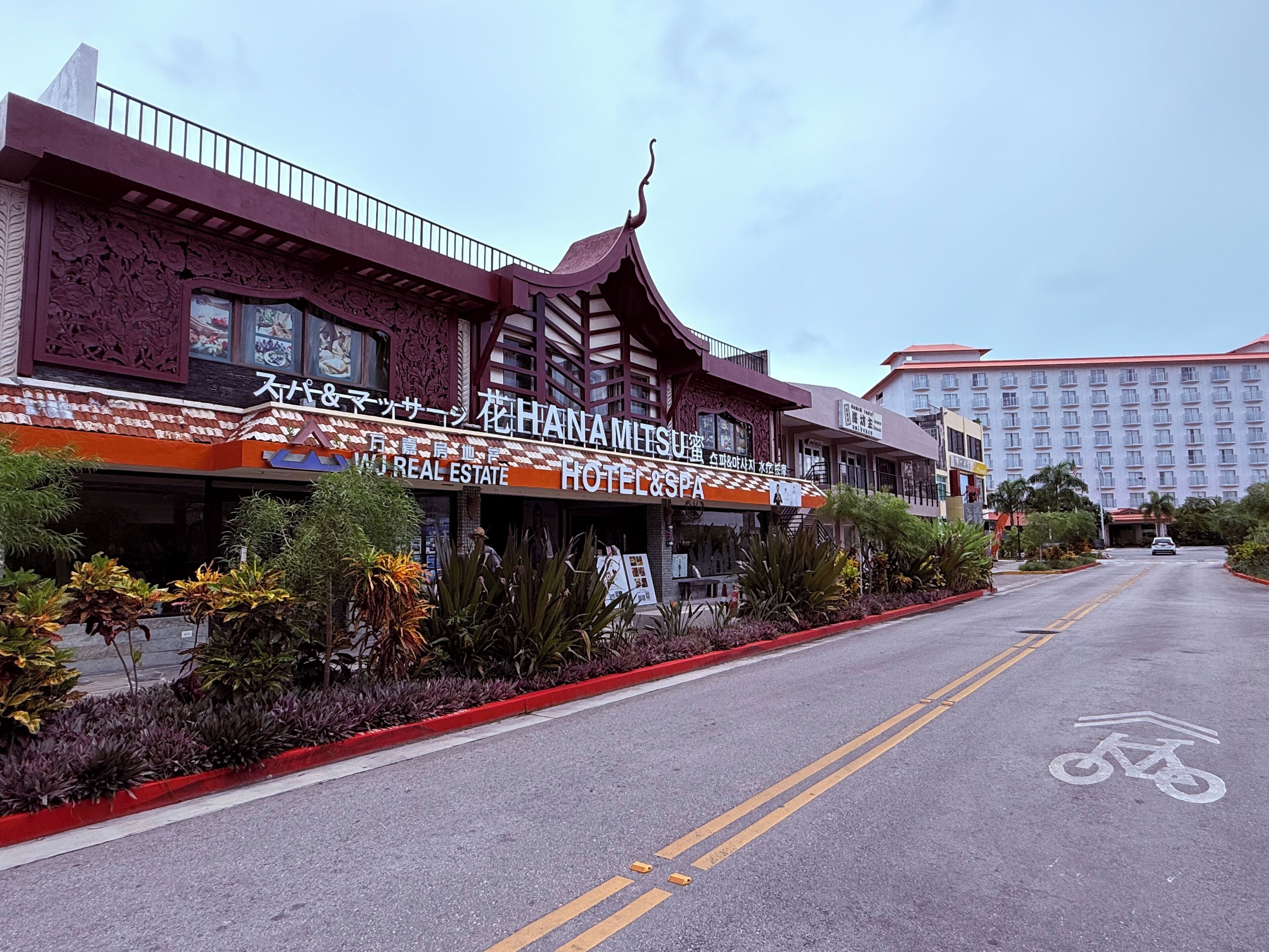 A hotel with a traditional architectural design, featuring a prominent sign for 'HANAMITSU HOTEL & SPA'.