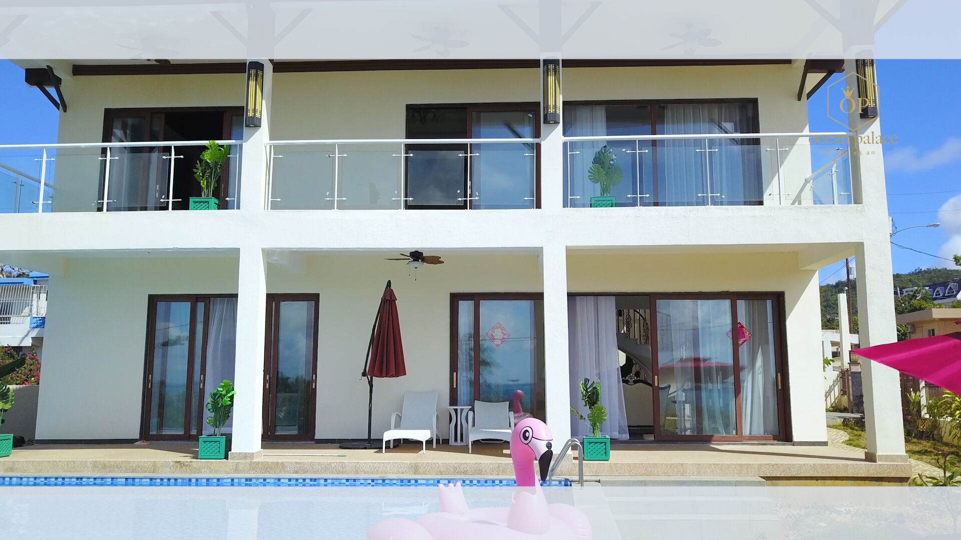Un edificio de dos pisos con balcones, piscina y mobiliario exterior.