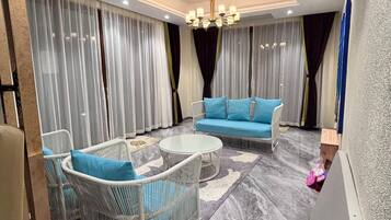 A modern living room with a sofa, two armchairs, a coffee table, and a chandelier.