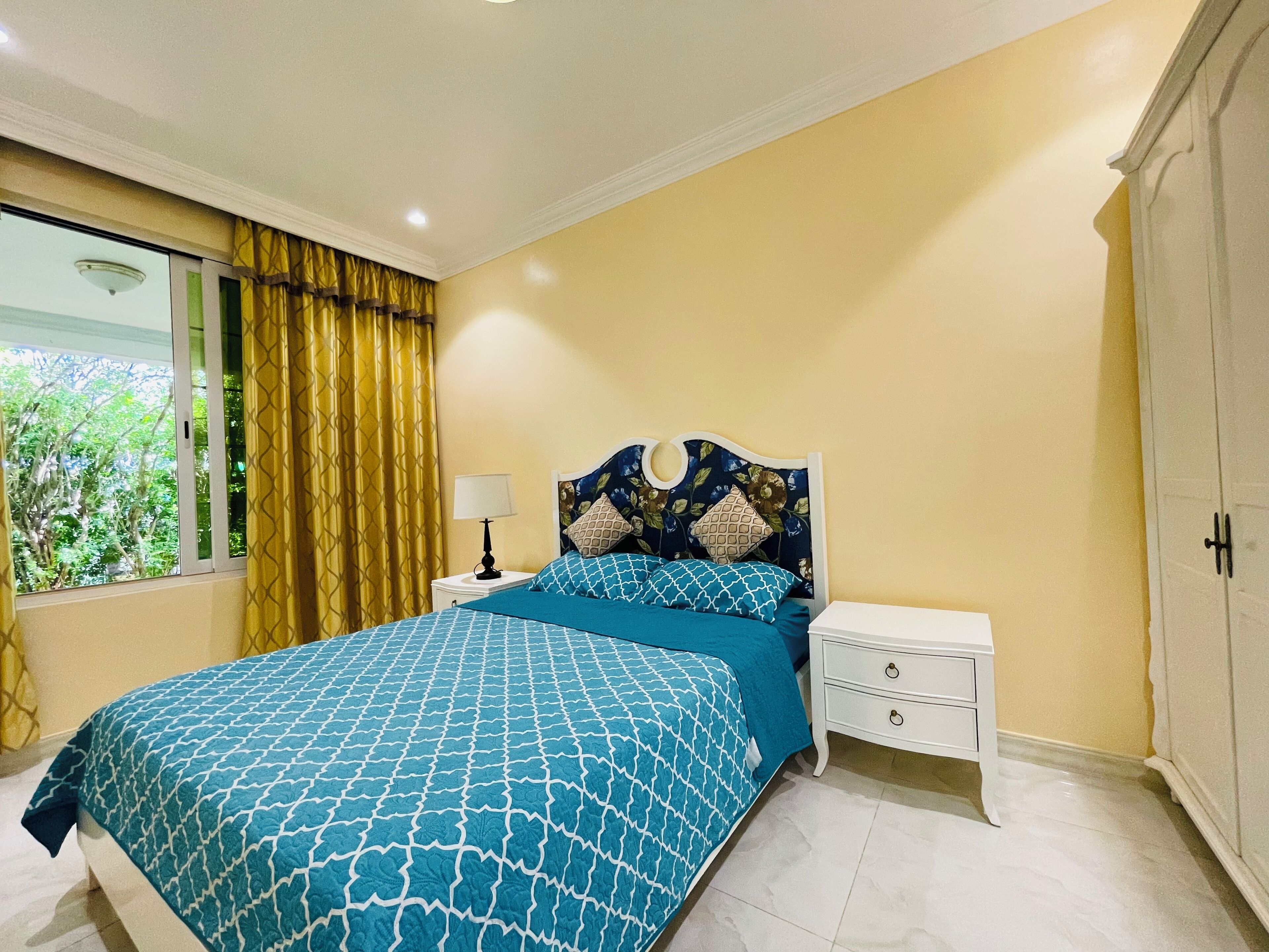 A bedroom with a bed, a nightstand, a lamp, and a wardrobe.