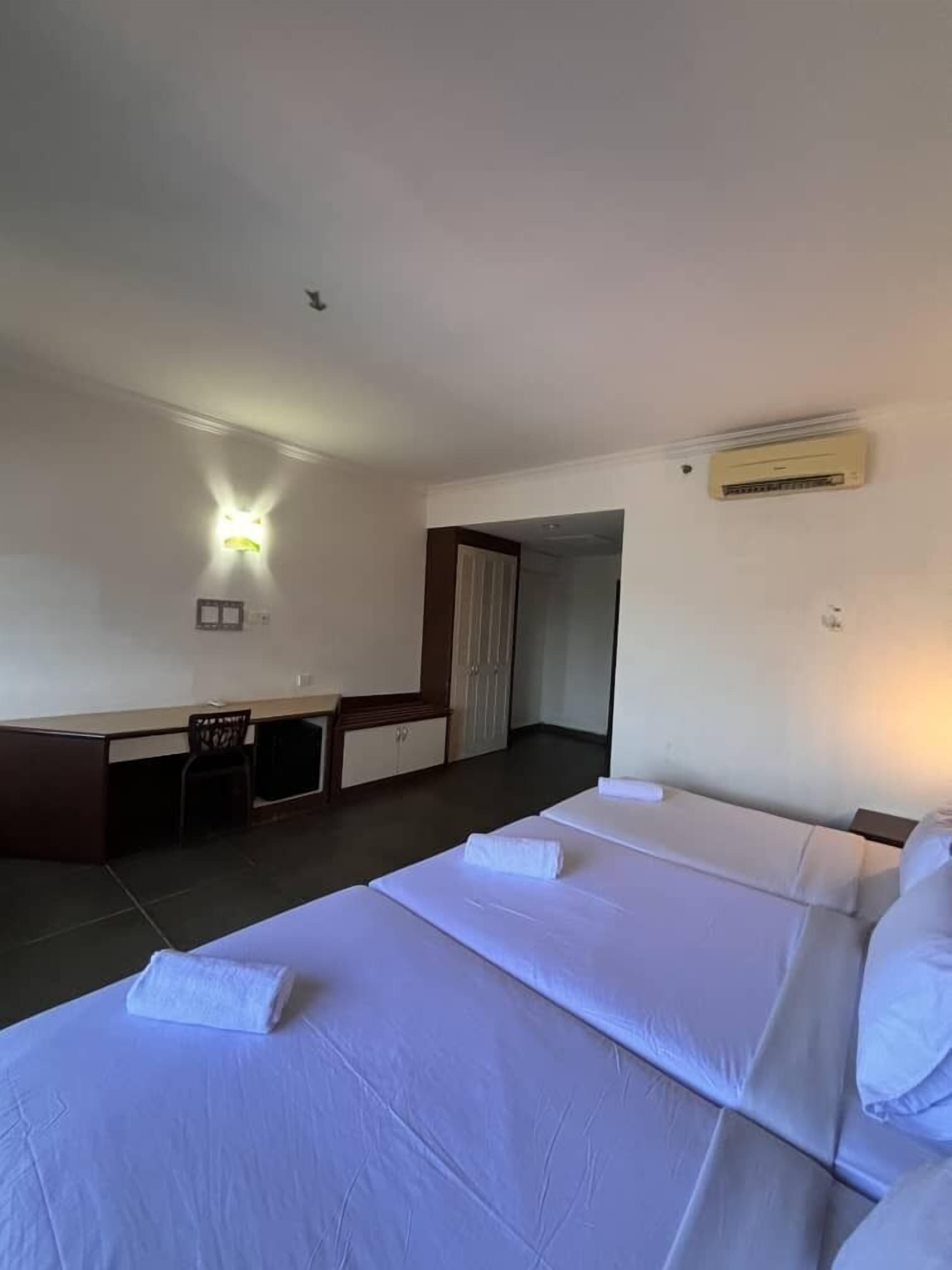 A hotel room with two beds, a desk, and a chair.