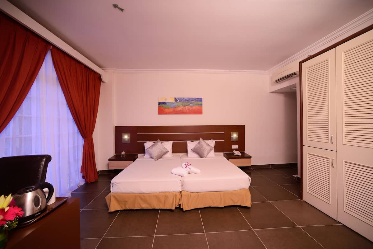 Quarto de hotel com cama, mesas de cabeceira, um quadro, escrivaninha com chaleira e guarda-roupa.