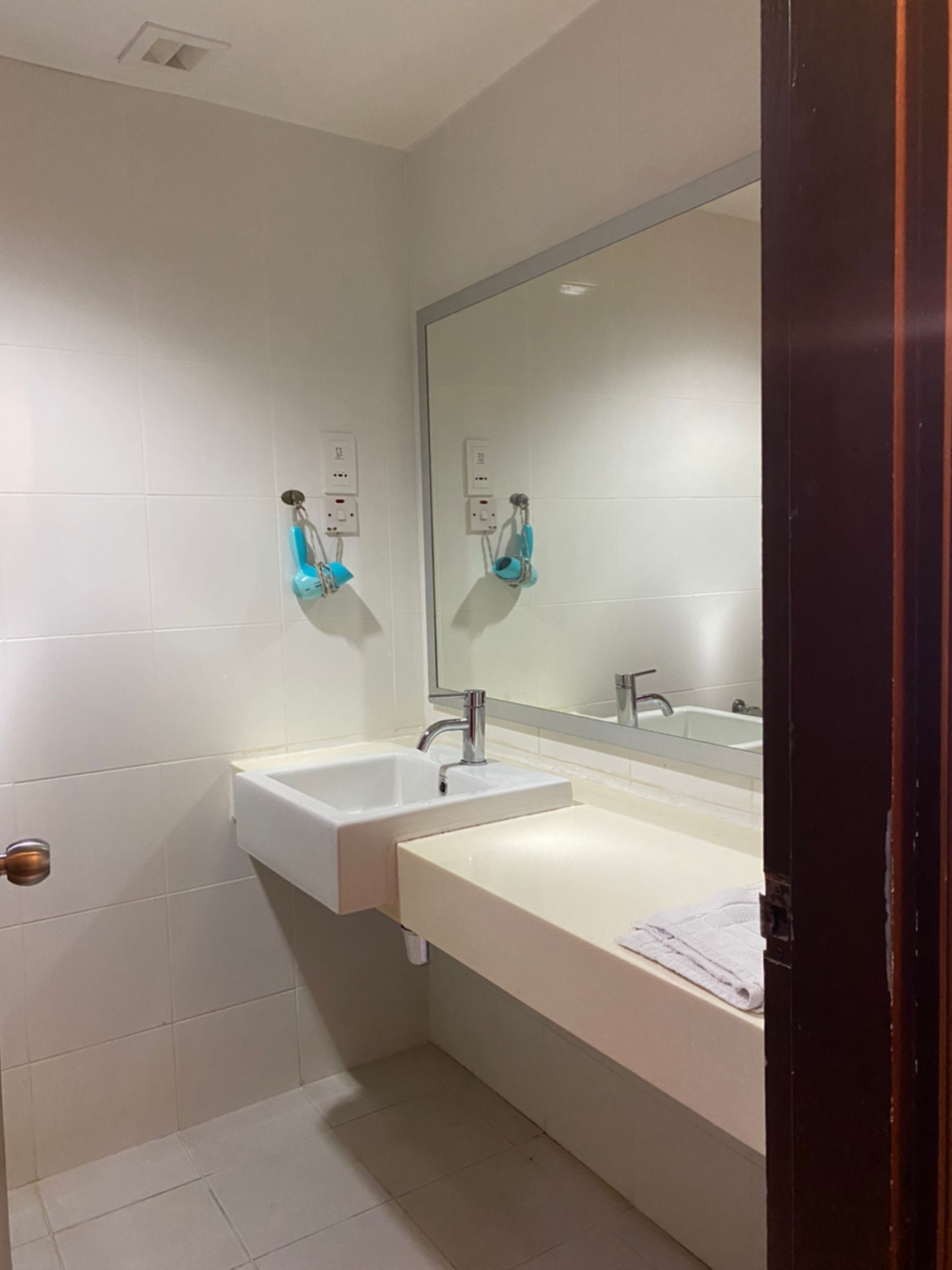 A bathroom with two sinks, a large mirror, and a towel rack.