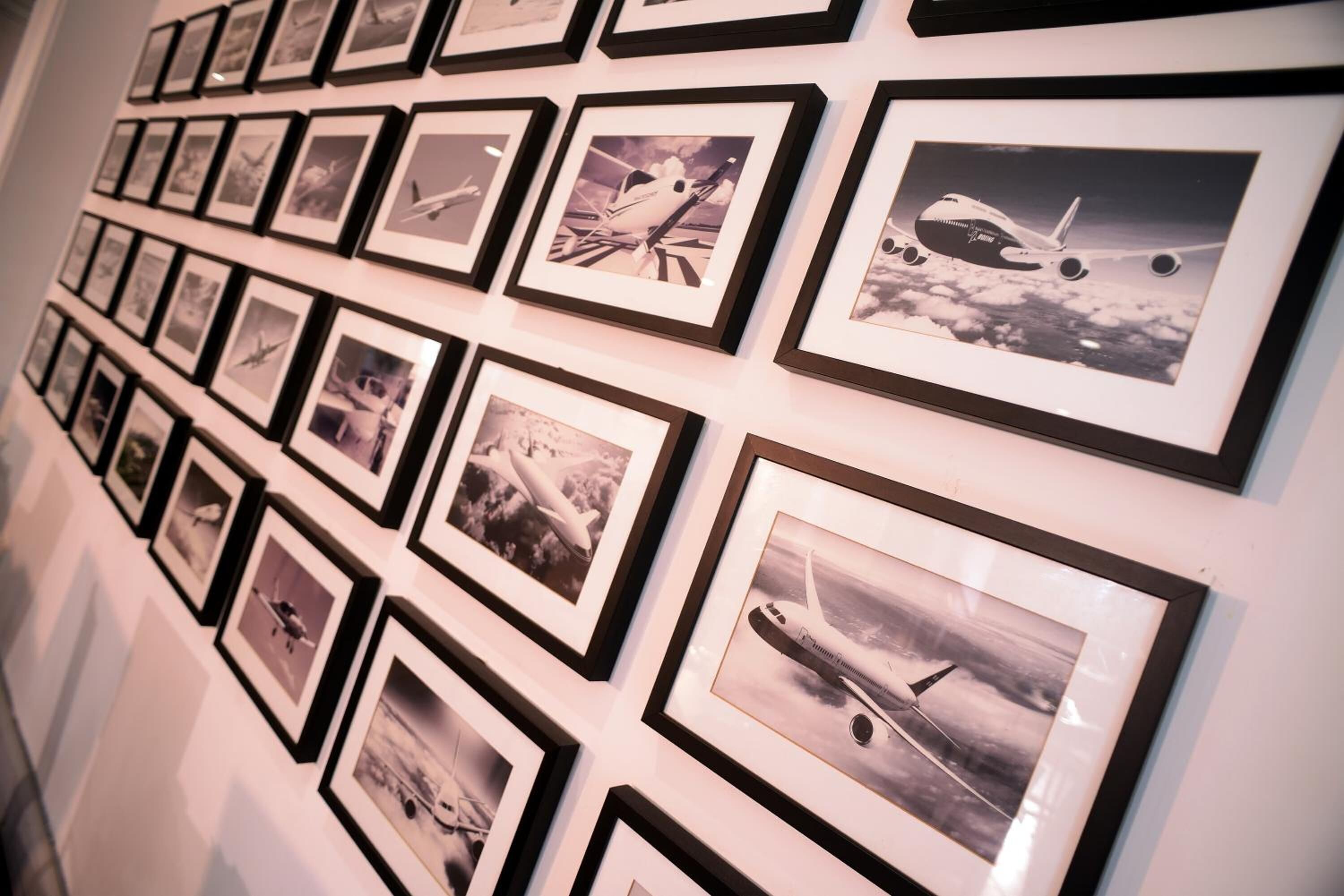 A wall with multiple framed photographs of airplanes.