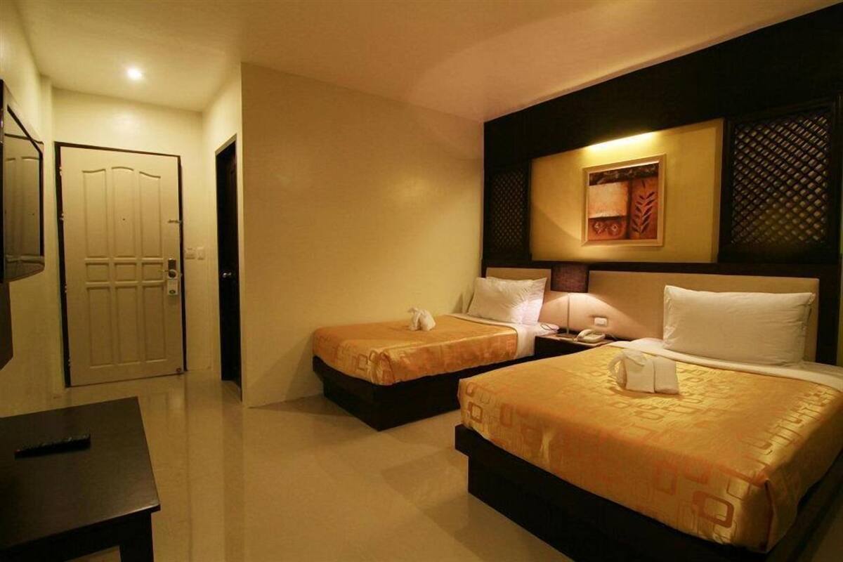 A hotel room with two beds, a desk, and a door.