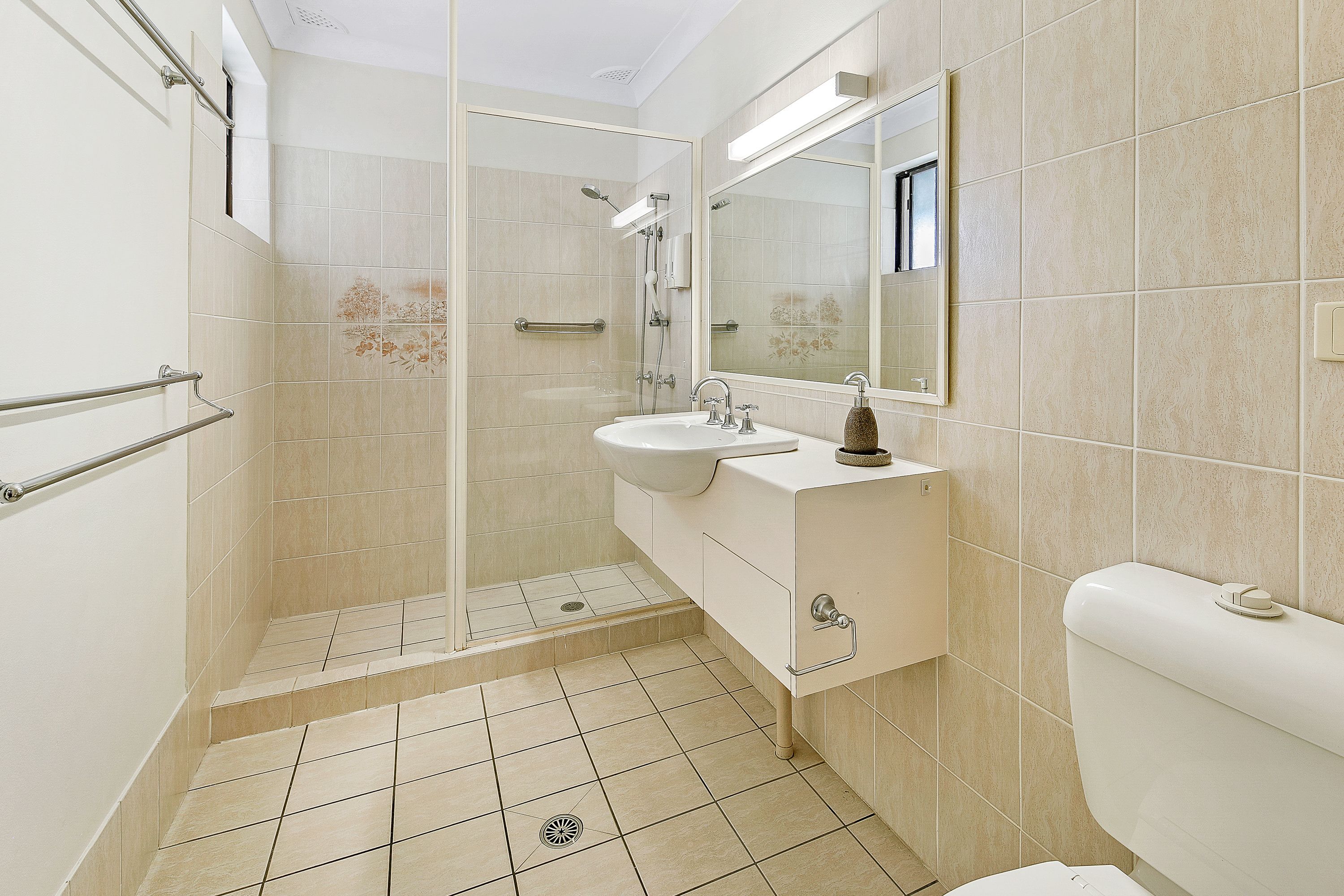 Een badkamer met een glazen douchecabine, een wastafel en een toilet.