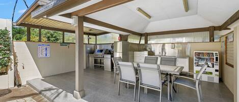 An outdoor patio area with a covered seating area, a vending machine, and a pool safety sign.