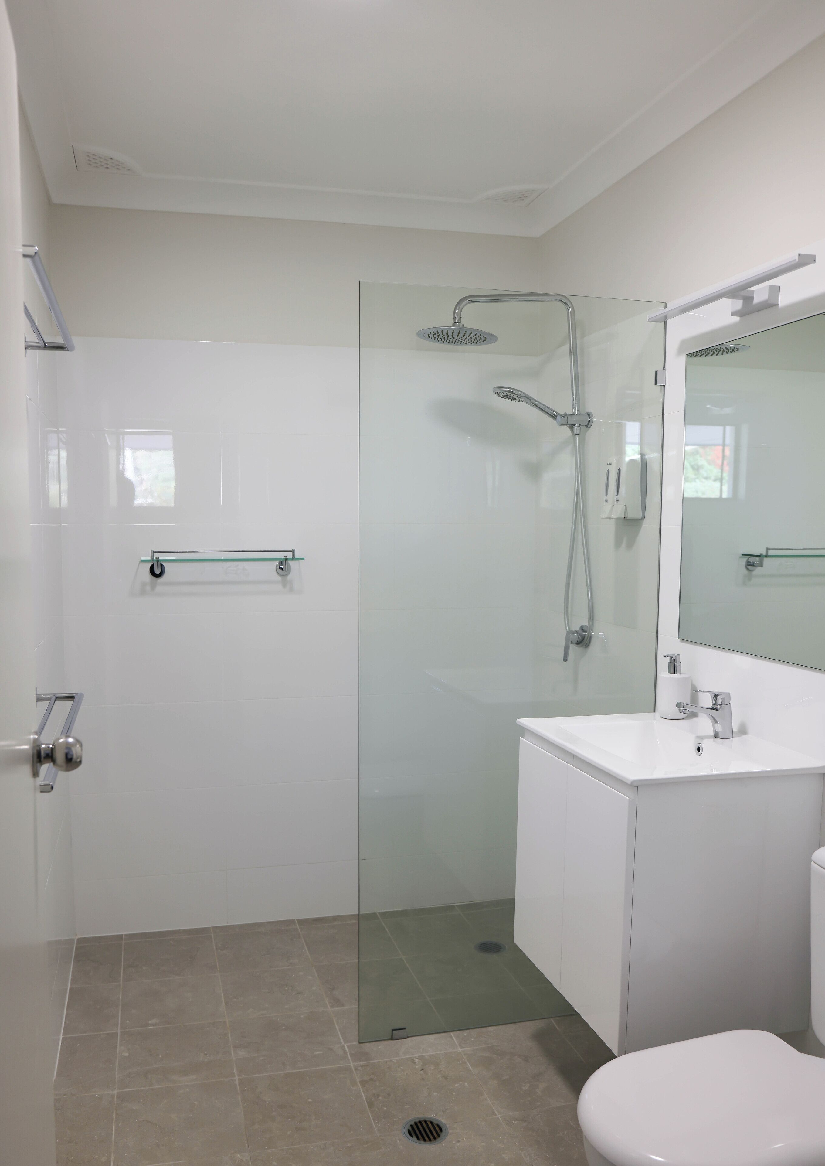 A modern bathroom with a glass-enclosed shower, a white sink, and a toilet.