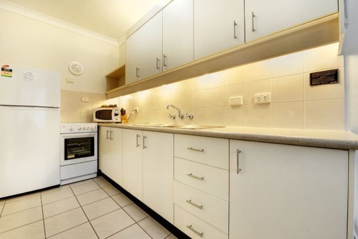 A kitchen with white cabinets, a microwave, a stove, and a refrigerator.