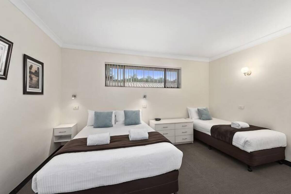 A hotel room with two beds, a window with a view, a desk, and a chair.