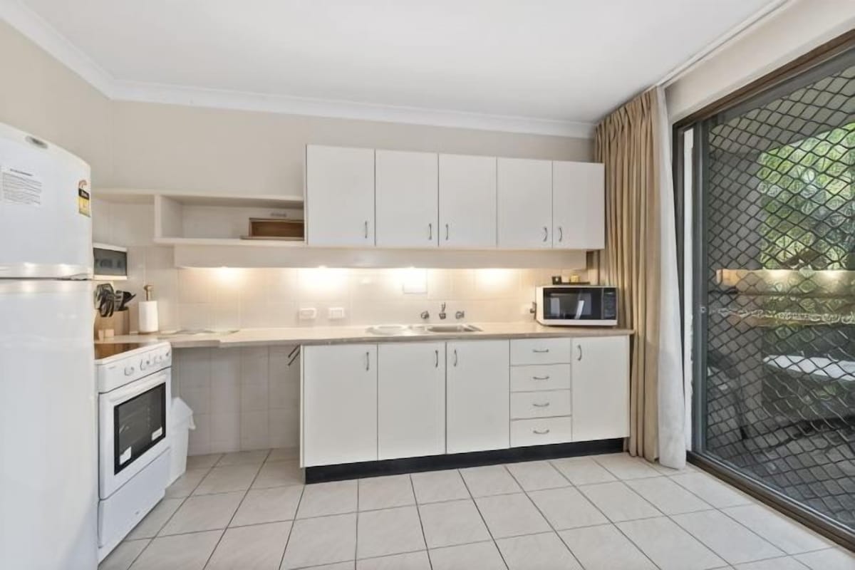 A modern kitchen with white cabinets, a microwave, and a sink.