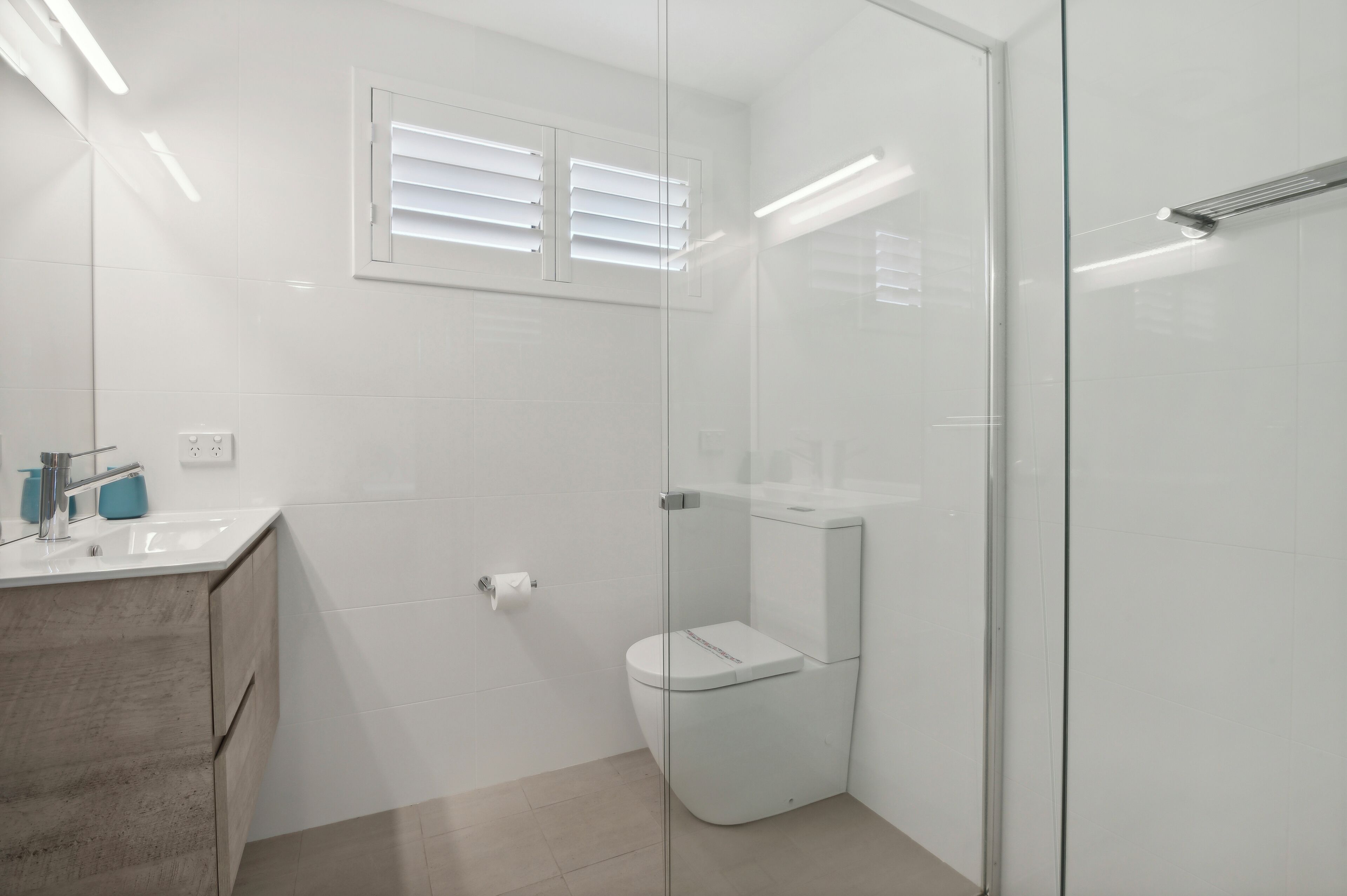 A modern bathroom with a glass shower enclosure, a toilet, and a sink with a mirror.