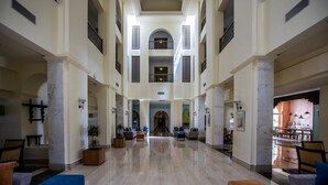 A spacious lobby with high ceilings, marble flooring, and seating areas on both sides.